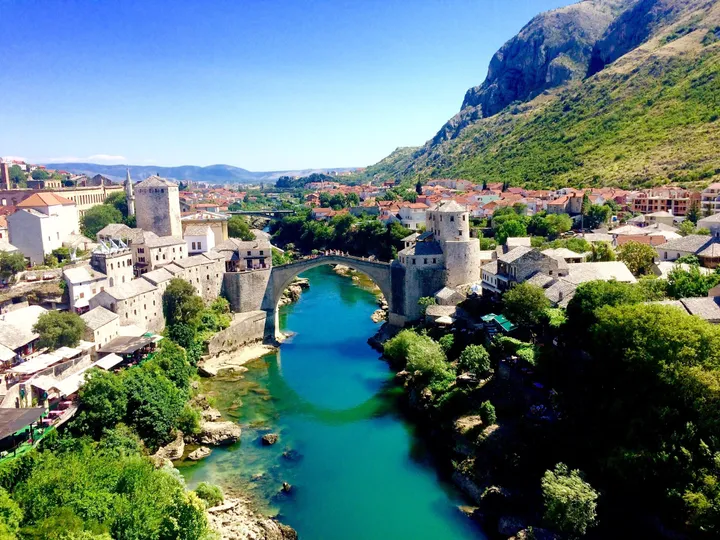 The stone Old Bridge arching over the turquoise Neretva River between Mostar’s hillside rooftops